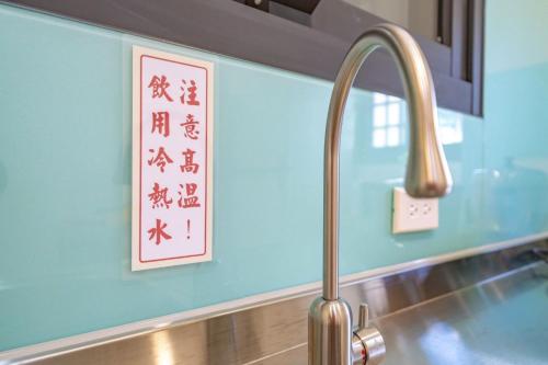 T'ung-koにある愛旅行民宿の蛇口と壁に看板が付いたキッチンシンク