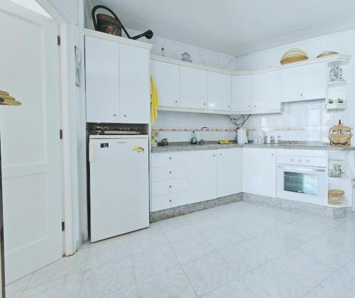 a kitchen with white cabinets and a white refrigerator at Luxor in Los Cristianos
