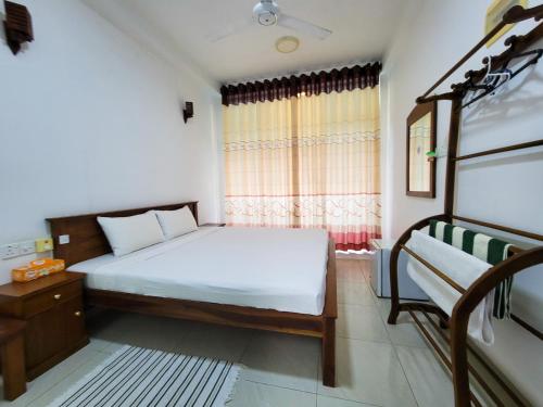 ein kleines Schlafzimmer mit einem Bett und einem Fenster in der Unterkunft Nuwan Inn in Hikkaduwa