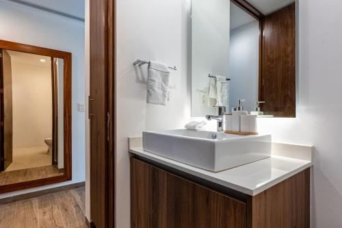 ein Badezimmer mit einem weißen Waschbecken und einem Spiegel in der Unterkunft The Leaf C108 in Playa del Carmen