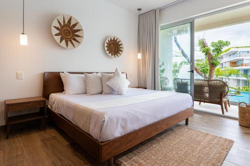 ein Schlafzimmer mit einem Bett und einer Glasschiebetür in der Unterkunft The Leaf C108 in Playa del Carmen