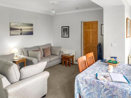 a living room with a couch and a table at Jasmine Cottage in Knitsley