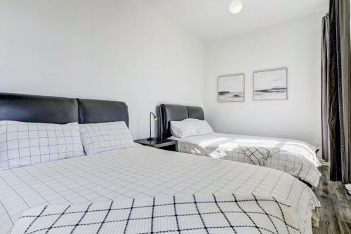 two beds in a room with white walls at Chez Mont Royal Apartments! in Montréal