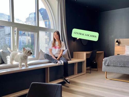 a woman sitting on a window sill with a dog at Citybox Bergen City in Bergen