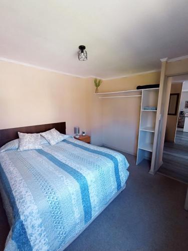 a bedroom with a bed with a blue and white comforter at El Hogar de Catagus in Talcahuano