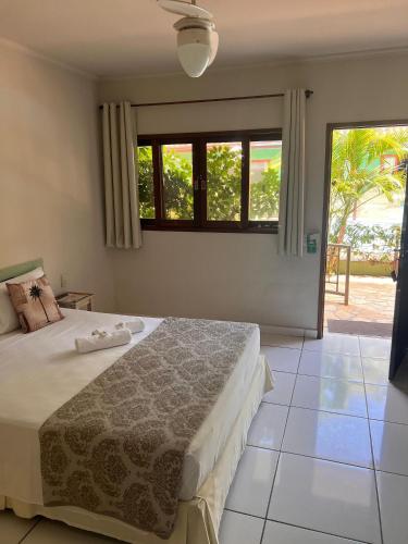 a bedroom with a bed and a large window at Pousada Morada da Praia - Ubatuba -Praia Grande in Ubatuba