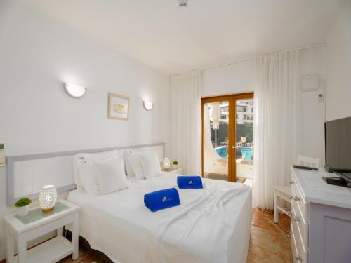 a white bedroom with a white bed with blue pillows at Akisol Olhos de Água Ocean in Albufeira