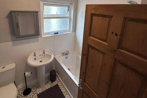 a bathroom with a sink and a toilet and a tub at 3 Bed House-Sleeps 5-Free Parking & Wi-Fi in Sketty