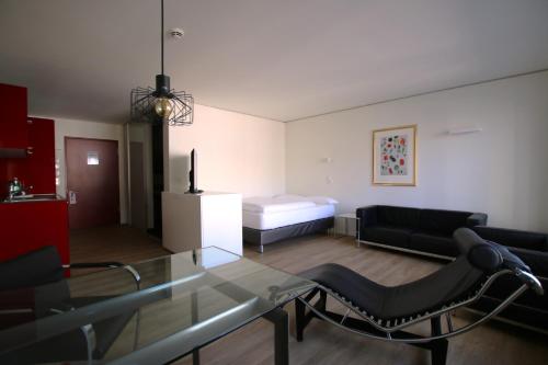 - un salon avec une table en verre et un lit dans l'établissement MAVO Hospitality Esslingen Berliner Straße, à Esslingen am Neckar