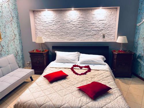 a bedroom with a bed with two red pillows at Bianca di Navarra House in Biancavilla