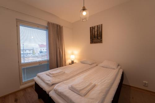 a bedroom with a bed with white sheets and a window at Aurora suites with AIR CONDITIONING in Rovaniemi