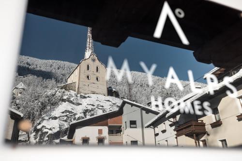 une église située au sommet d'une montagne avec des bâtiments dans l'établissement MYALPS Historical, à Oetz