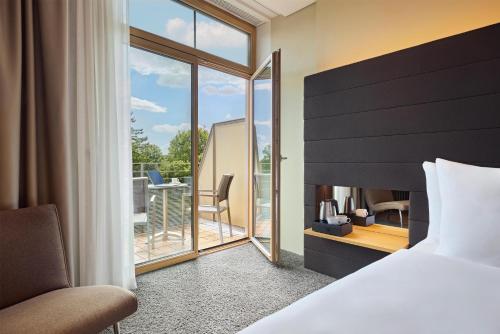 a hotel room with a bed and a balcony at Dorint Parkhotel Jordanbad in Biberach an der Riß