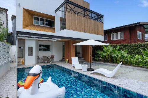 a house with a pool with a inflatable swan in it at VivaDeva , Pool Villa In Nimman 4BR Near MAYA MALL in Chiang Mai