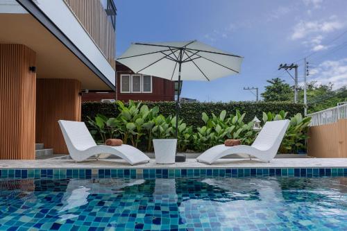 two chairs and an umbrella next to a swimming pool at VivaDeva , Pool Villa In Nimman 4BR Near MAYA MALL in Chiang Mai