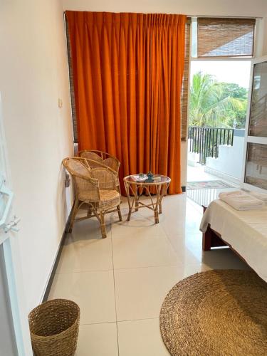 ウェリガマにあるBe Happyのオレンジ色のカーテンとベッドと椅子のある寝室