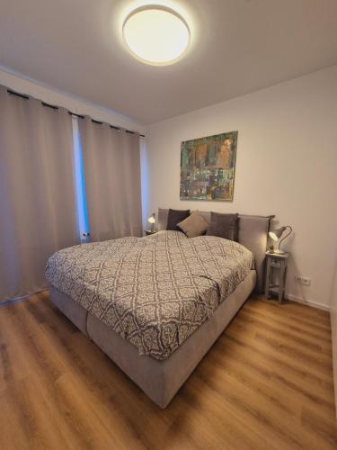 a bedroom with a large bed with a wooden floor at Heinsberg City Apartment - Stil trifft Farbe! in Heinsberg