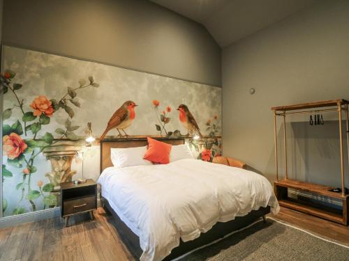 a bedroom with a bed with birds on the wall at Robins Rest at The Lodge in McGrathʼs Cross Roads