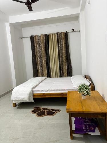 a bedroom with a bed and a table and a window at Grazioso Home Stay in Guwahati