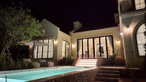 a house with a swimming pool at night at La Moon Da Villa Khaoyai in Ban Bung Toei