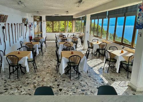 a dining room with tables and chairs and windows at Belvedere in Pisciotta