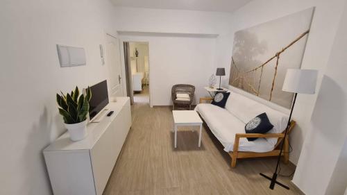 ein Wohnzimmer mit einer weißen Couch und einem Tisch in der Unterkunft Arrecife Apartamento centrico in Arrecife