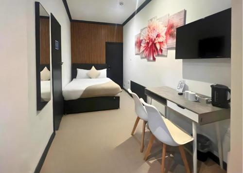 une chambre avec un bureau et un lit et un bureau et des chaises dans l'établissement Amsterdam Hotel, à Londres