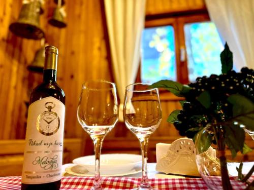 a bottle of wine and two wine glasses on a table at Zlatarsko Miriste in Nova Varoš