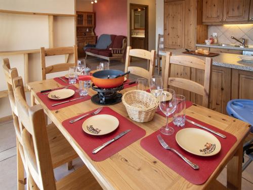 a wooden table with plates and wine glasses on it at Apartment Ardève 7 by Interhome in Ovronnaz
