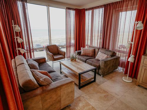 a living room with two couches and a table at Apartment De Zeeparel by Interhome in Egmond aan Zee