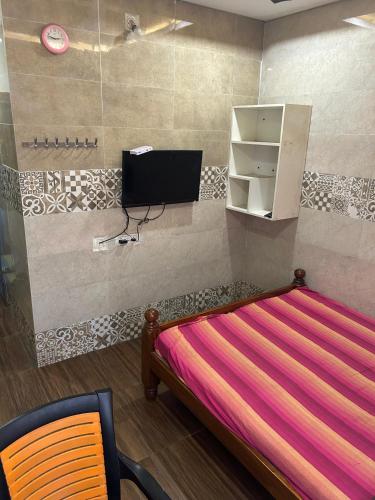 a bedroom with a bed and a tv and a chair at Jsn Palace in Chennai
