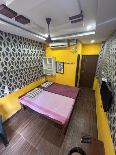 a bed in a room with a yellow wall at Jsn Palace in Chennai