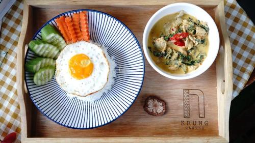 een dienblad met een bord eten, met een ei en wortels bij Krung Boutique Hotel in Bangkok