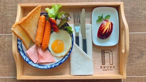 een houten dienblad met een bord eten, waaronder een ei en groenten bij Krung Boutique Hotel in Bangkok