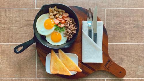 een koekenpan met eieren en brood op een tafel bij Krung Boutique Hotel in Bangkok