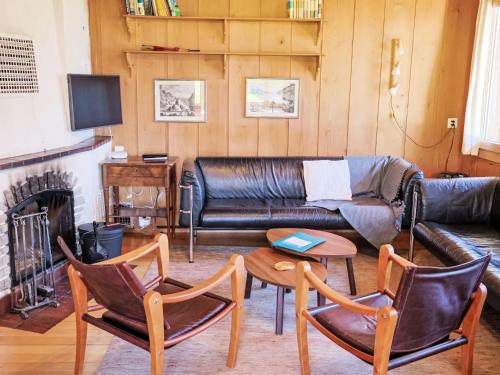 a living room with a leather couch and chairs at Chalet Chalet Pitschun by Interhome in Grindelwald