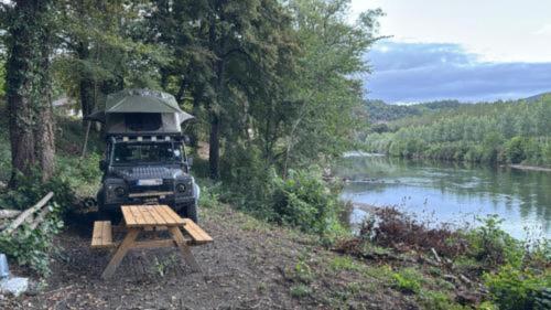 a truck parked next to a picnic table next to a river at Le petit nid des Templiers in Montsaunès