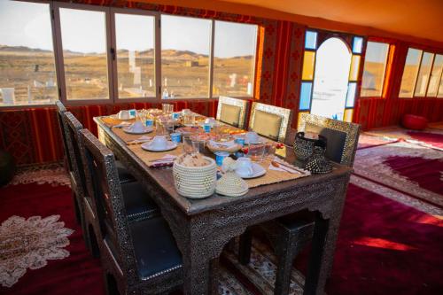 een tafel met borden en schalen erop in een kamer met ramen bij Typical Luxury Desert Camp in Merzouga