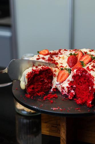 Un trozo de tarta de fresa en un plato con una espátula. en Comfort Hotel Campos dos Goytacazes, en Campos dos Goytacazes