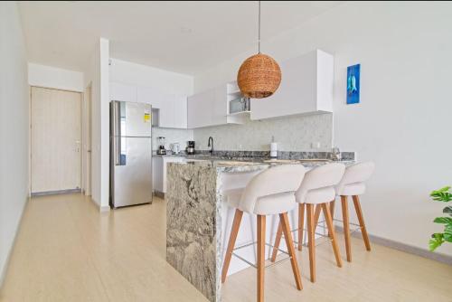 eine Küche mit einer Theke mit Hockern und einem Kühlschrank in der Unterkunft luxury apto sierra beach pozos colorados in Playa Bello Horizonte