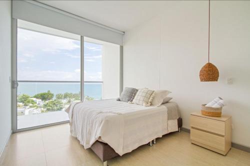 ein weißes Schlafzimmer mit einem Bett und einem großen Fenster in der Unterkunft luxury apto sierra beach pozos colorados in Playa Bello Horizonte
