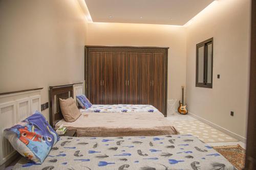 a bedroom with two beds and a guitar in it at فيلا غريس الجديدة 3 غرف نوم ومسبح in Jeddah