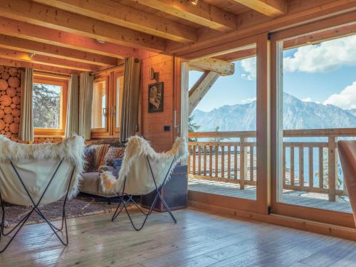 a living room with chairs and a balcony with mountains at Chalet Etoile by Interhome in Nendaz