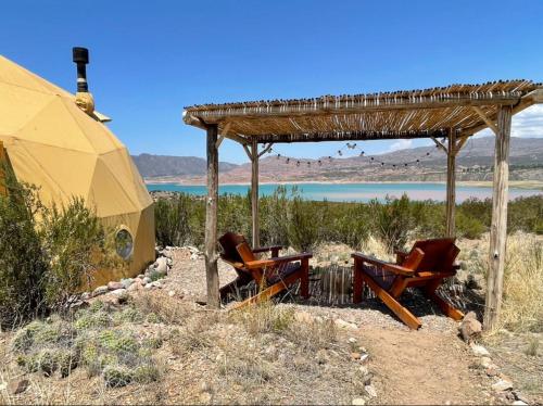 two chairs sitting under a shelter next to a tent at El Nido Domos Potrerillos in Potrerillos
