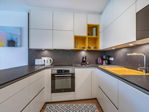 een keuken met witte kasten en een spoelbak bij Apartment Top 5 Alpe maritima Seeblick-Bergkulisse by Interhome in Annenheim