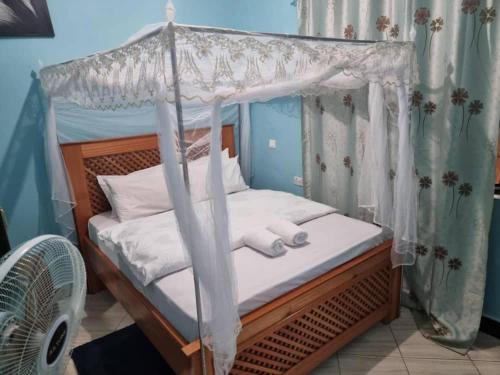 a bedroom with a canopy bed with white sheets and pillows at Kisanga Homestay in Moshi