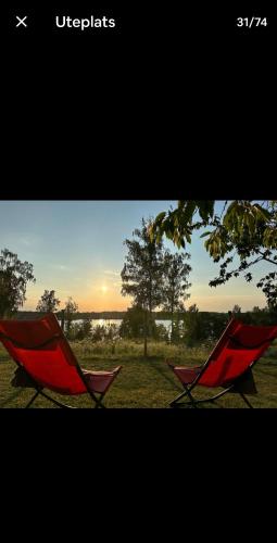 two red chairs sitting in a field with the sunset at Tofta in Växjö