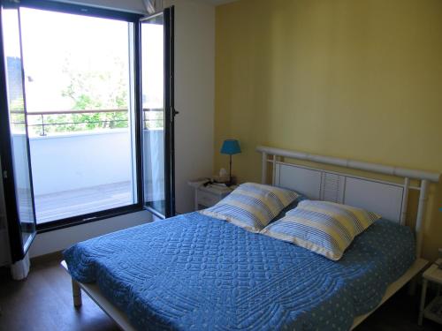 une chambre avec un lit avec une couette bleue et une fenêtre dans l'établissement Résidence Beauséjour, à Carantec