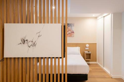 オビエドにあるSilken Apartamentos Goyaのベッドと壁に絵が飾られた寝室