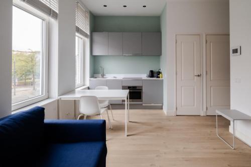 a kitchen with a white table and a blue couch at Your Modern Retreat Close to Rotterdam City Center in Rotterdam